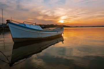 Colorful sunset at the ocean with specular reflection with fisherman boat