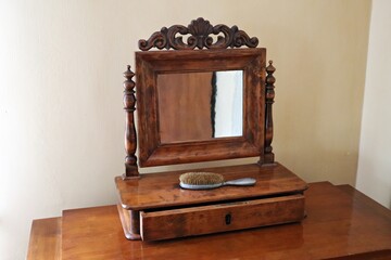 On the table is an old wooden box with a mirror and a massage brush