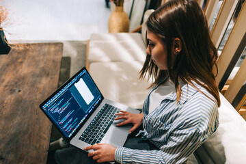 Young woman mobile developer with laptop, writes program code on a computer, programmer work in...