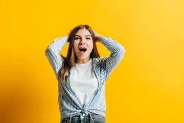 Portrait of excited young woman surprised by something expresses shock and surprise, isolated on yellow background with copy space.