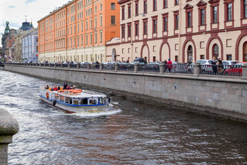 St. Petersburg, Russia - May 02, 2021. A pleasure boat sails along the Griboyedov Canal past historic buildings in the city center. Selective focus.
