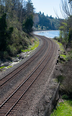 Railroad tracks near beach landscape with the tracks set on a curve in a vertical format.
