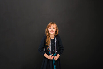 Girl kid 8-9 y.o. with black glasses and with a books looking at camera in isolation on a black background. Back to school.