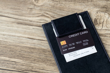 The black credit card on blank bill paper in  leather black bill receipt. Receipt Holder with credit card on cafe or Restaurant. 