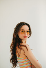 Portrait of attractive stylish woman in sunglasses with long brunette hair in studio.