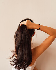 Vertical shot of a brunette woman making a ponytail