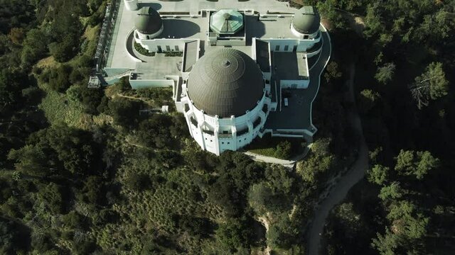 Aerial Tilt Up Of Famous Griffith Observatory On Mountain, Drone Flying Backward Over Landmark Against Sky On Sunny Day - Los Angeles, California