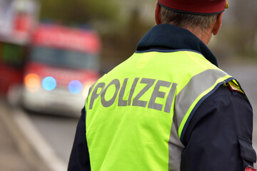 Polizist von hinten mit Feuerwehr-Fahrzeug in Oberösterreich, Österreich, Europa - Police officer from behind with fire service vehicle in Upper Austria, Austria, Europe