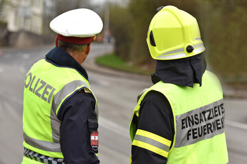 Polizist und Feuerwehrmann von hinten in Oberösterreich, Österreich, Europa - Police officer and firefighter from behind in Upper Austria, Austria, Europe