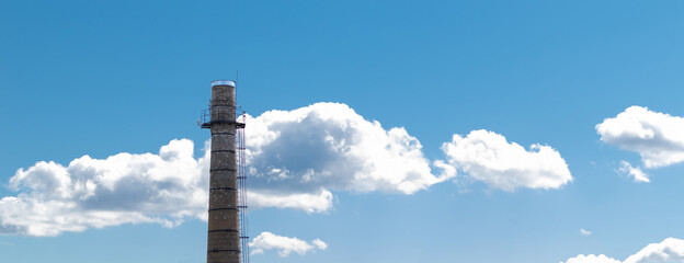 A large brick chimney on a background of blue sky with clouds