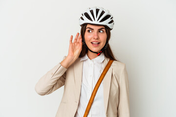 Young caucasian woman riding a bicycle to work isolated on white background trying to listening a gossip.