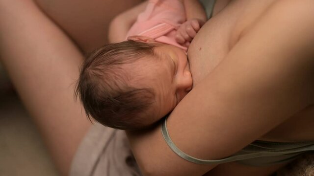Close-up of newborn baby being milked by a young mother, top view