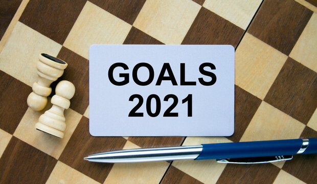 Business card with text Goals 2021 on a chess board with pen and eyeglasses