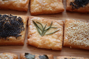 Domowe krakersy ozdobione listkami ziół, sezamem, makiem i solą