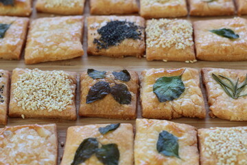Homemade crackers decorated with herb leaves, sesame seeds, poppy seeds and salt