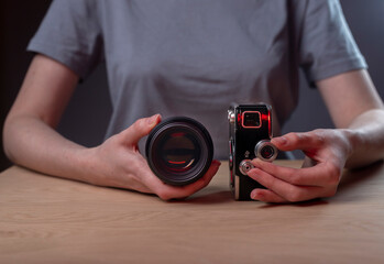 Photographer showing two cameras, vintage old one and modern lens. Photograph development concept.