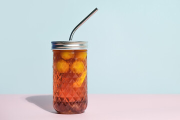 Stewed-fruit in glass with metal straw. Compote refreshing summer non-alcoholic drink on minimal coloured background. Copy space.