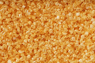 Texture of golden cane sugar with solid background in full screen.