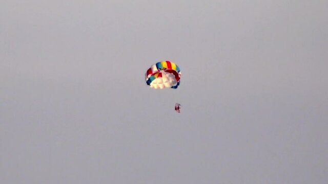 A couple having fun parasailing at sunset.