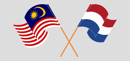 Crossed and waving flags of Malaysia and the Netherlands