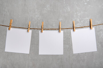 Blank white notes of paper hang with clothespins on rope. Copy space. Place for your text.