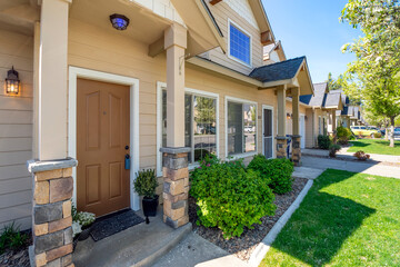 A home for sale with a lockbox on the doorknob within a row of suburban townhomes in the Inland Northwest.