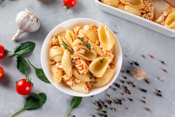Baked feta pasta in a plate. Fetapasta on a light background. New, popular dinner dish. Top view, copy space.
