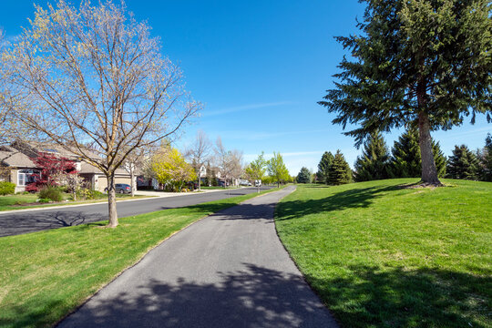 A Suburban Street Of Homes In A Subdivision Across From A Park And Walking Trail Path In The Town Of Coeur D'Alene, Idaho, USA