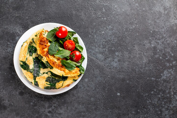 Frittata made of eggs, cheese and spinach salad. Frittata - italian omelet on a plate on a gray background. Ketogenic, keto food, menu recipe place for text, top view