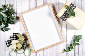 Artwork poster print wood frame. On-trend farmhouse theme flatlay craft product mockup with farmhouse style decor, stack of books, and bow on a white wood background. Negative copy space. - obrazy, fototapety, plakaty