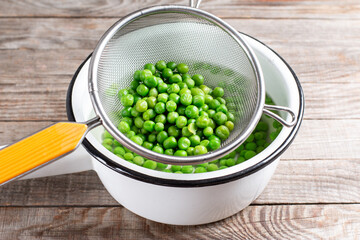 Green peas in a colander. Boiled or blanched vegetables on a table