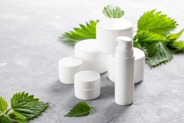 Natural spa, herbal cosmetics. Nettle lotion, shampoo and cream in a bottle and nettles leaves. Medicinal herb for health and beauty, skin care and hair treatment