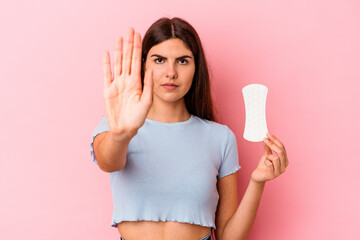 Young caucasian woman holding a compress isolated on pink background standing with outstretched hand showing stop sign, preventing you.