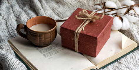 Gift vintage box together with an open book and a cup of coffee on the table on a light background. Natural light. Festive concept.