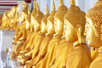 A long line of golden statues of the Buddha at Buddhist temple in Thailand, a portrait of side view, Photharam, Thailand.
