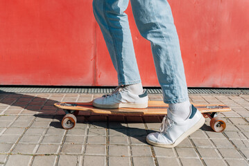 close-up take of the feet of an unrecognizable man on a skateboard on the street sidewalk. He is projecting a hard shadow on the floor