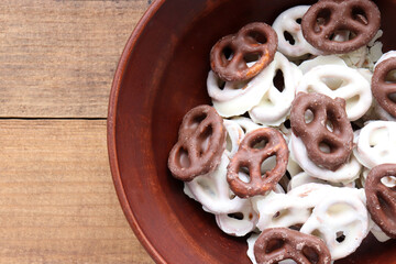 White and dark salted chocolate covered mini pretzels in a bowl on wood table. Homemade assorted mini pretzel chip cookies on wooden background. Top view, copy space

