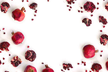 Fresh red pomegranate garnets with pieces and seed on white background with space for text. Top view, flat lay