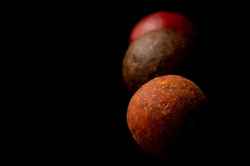 Protein balls for fishing carps of different colors on a black background.
