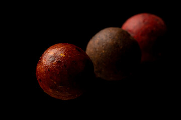 Protein balls for fishing carps of different colors on a black background.