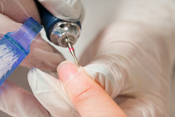 Woman in a nail salon receiving a manicure by a beautician with nail file. Beauty and hand care close-up.