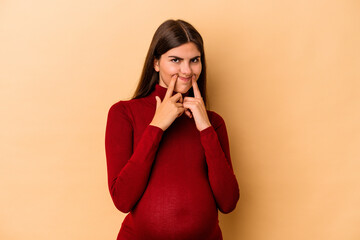 Young caucasian pregnant woman isolated on beige background doubting between two options.