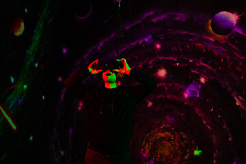 Portrait of a young man in 3D virtual reality glasses enjoy the game. Neon lights are red and green. The concept of connecting technology with science, augmented future