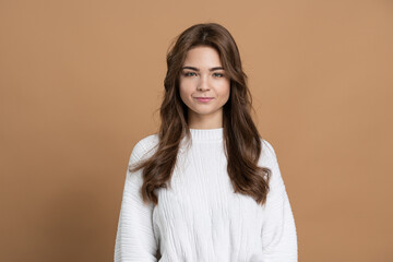 Fototapeta premium Attractive young girl with brown hair on a brown background. Beautiful girl isolated on a blank wall