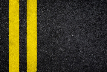 Top view of dark wet asphalt road with double yellow line. High resolution full frame textured...