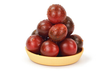 A slide of black tomatoes, folded in a slide on a wooden plate. Water droplets glisten on the peel