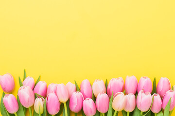 Greeting card. Border of pink tulips on a yellow background. Mothers Day, Valentines Day, birthday concept, flat lay