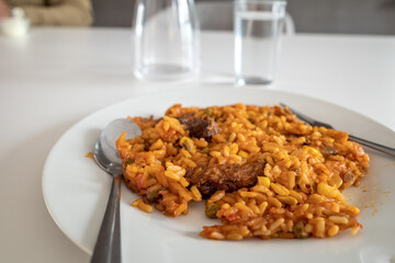 Selective focus, instant food, Cevapcici and red spicy rice on white dish and canteen's white table. 