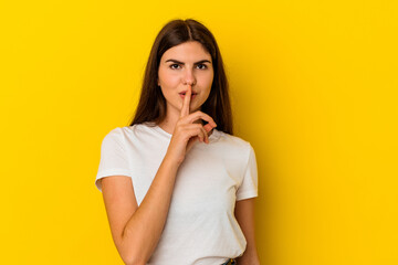 Young caucasian woman isolated on yellow background keeping a secret or asking for silence.