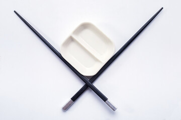 Black wooden sushi sticks with sauce saucer. View from above.